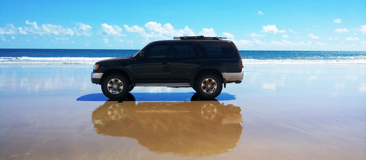 A black SUV parked on the beach. 
